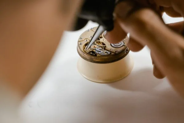 Technician repairing delicate watch mechanism using fine precision screwdrivers